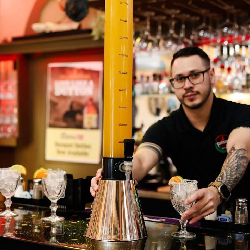 Bartender serving a drink from a large beverage dispenser at Potrillo's Mexican Grill.