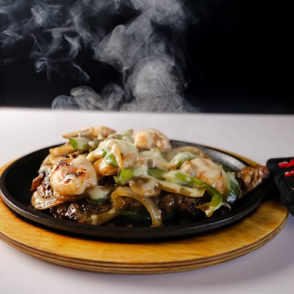 Sizzling Potrillo's Mexican Grill fajitas with shrimp, steak, onions, peppers, and melted cheese.