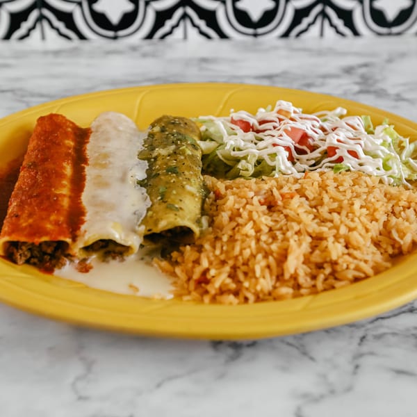 Three enchiladas with red, white, and green sauces, rice, and salad on a yellow plate.