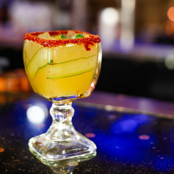 Cucumber margarita with a chili-lime rim, garnished with cucumber slices and chili flakes.