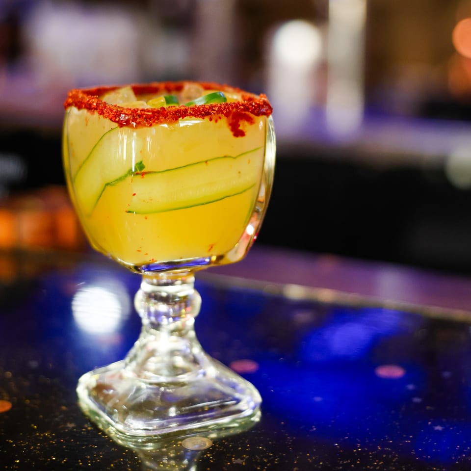 Cucumber margarita with a chili-lime rim, garnished with cucumber slices and chili flakes.