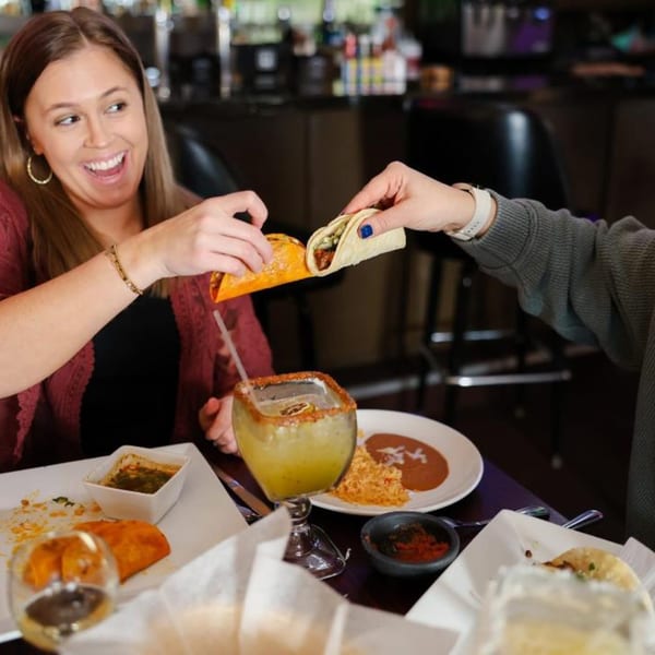 Two people sharing tacos and drinks at Potrillo's Mexican Grill, with plates of food on the table.