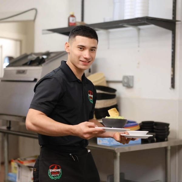 Smiling Potrillo's Mexican Grill staff member holding a bowl of guacamole with tortilla chips.