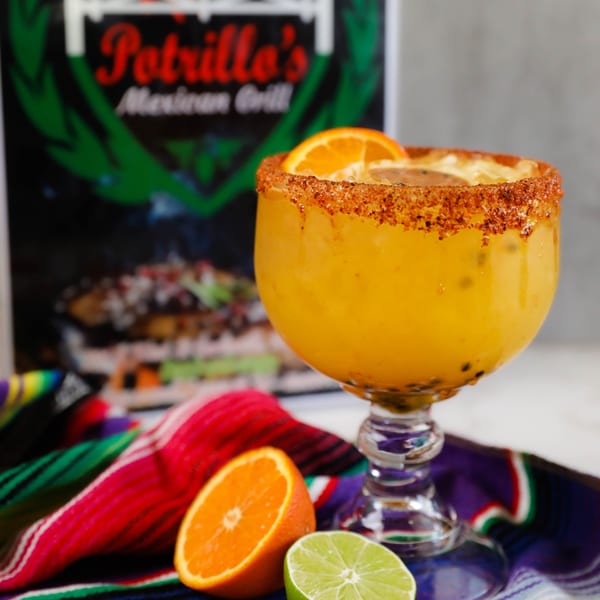 Potrillo's Mexican Grill's mango margarita with a chili-lime rim, orange, and lime on a colorful serape.