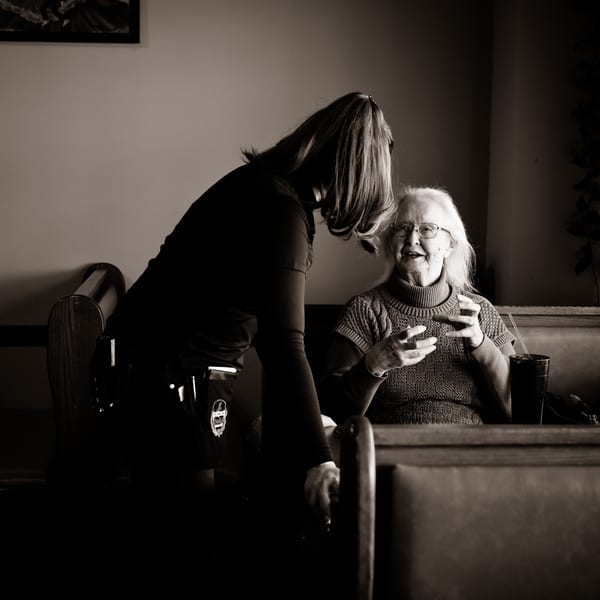 A server at Potrillo's Mexican Grill speaks with an elderly woman seated in a booth.