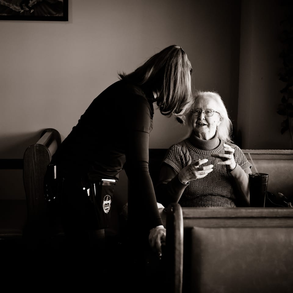 A server at Potrillo's Mexican Grill speaks with an elderly woman seated in a booth.