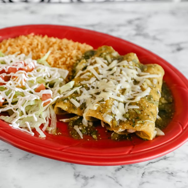 Potrillo's Mexican Grill's enchiladas with green sauce, cheese, rice, and a side salad on a red plate.