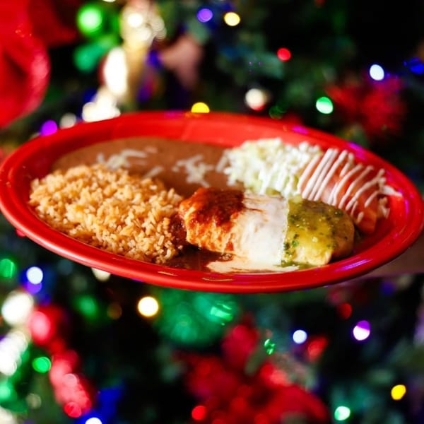 Potrillo's Mexican Grill enchiladas with red and green sauce, rice, and beans on a red plate.