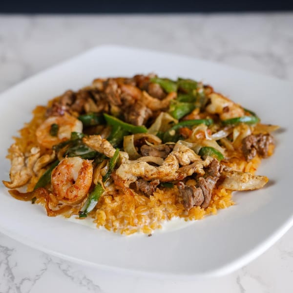 Potrillo's Mexican Grill's fajita dish with shrimp, chicken, beef, peppers, and onions over rice.