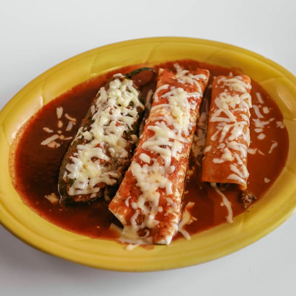 Three cheesy enchiladas and a chile relleno covered in red sauce on a yellow plate.