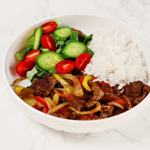 Potrillo's Mexican Grill's fajita bowl with steak, peppers, onions, rice, and a side salad.