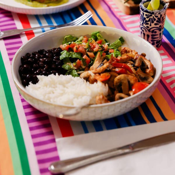 Potrillo's Mexican Grill's colorful bowl with black beans, rice, lettuce, pico de gallo, and chicken fajitas.