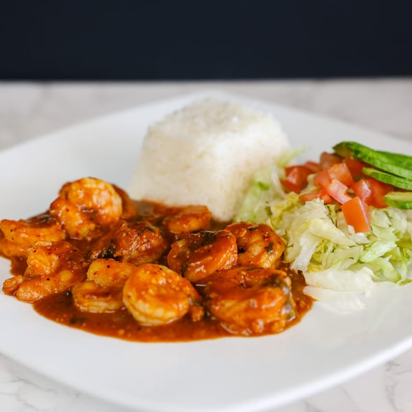 Potrillo's Mexican Grill's shrimp dish with rice, lettuce, diced tomatoes, and avocado slices.