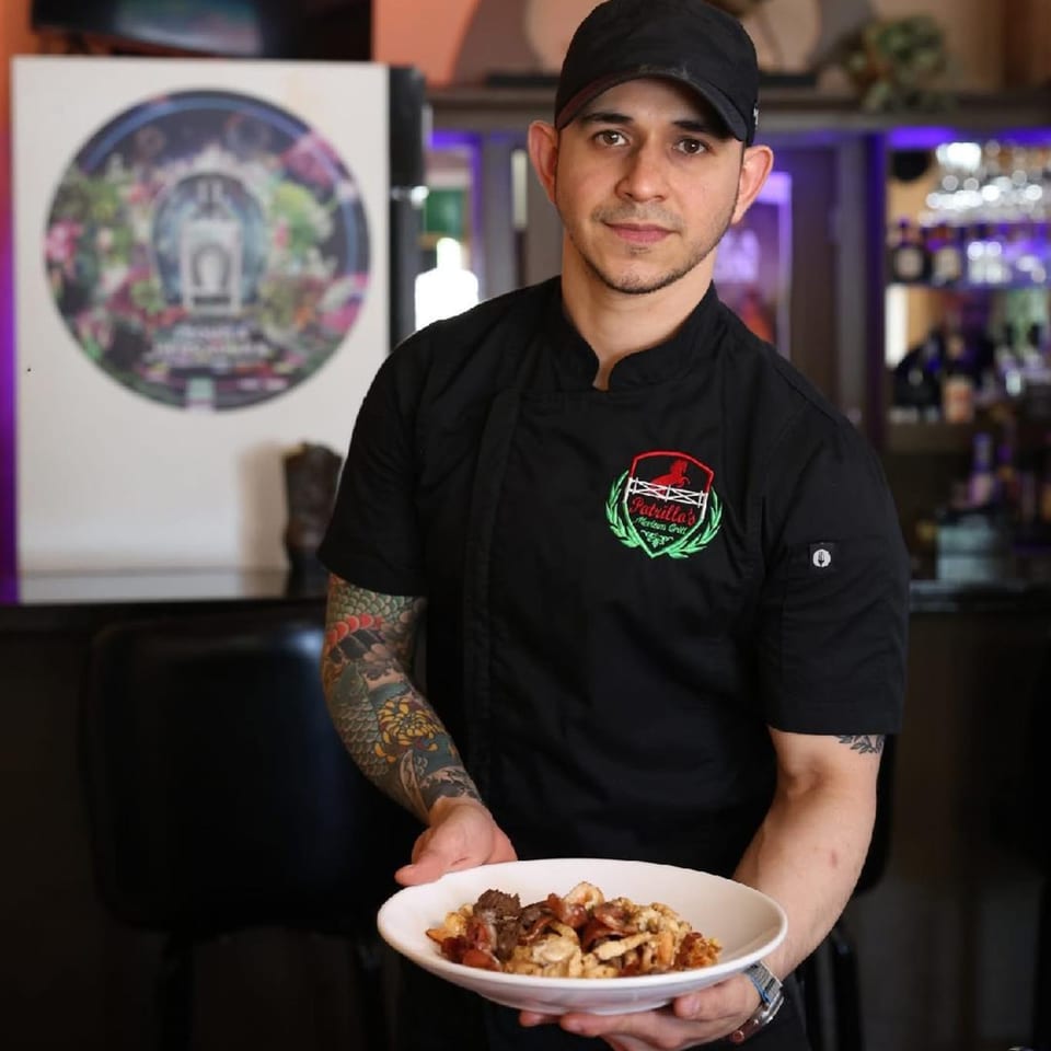 A Potrillo's Mexican Grill chef in a black uniform and cap holds a plate of food.