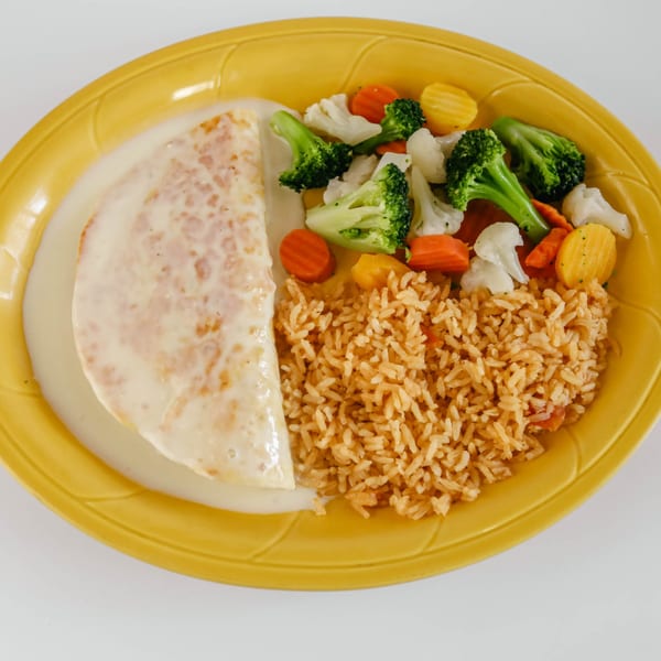 Chicken dish with creamy sauce, Mexican rice, and steamed vegetables on a yellow plate.