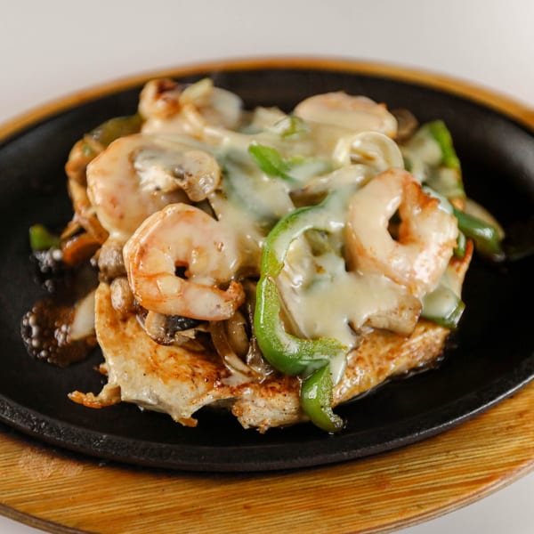Potrillo's Mexican Grill's sizzling fajita skillet with shrimp, chicken, bell peppers, mushrooms, and melted cheese.